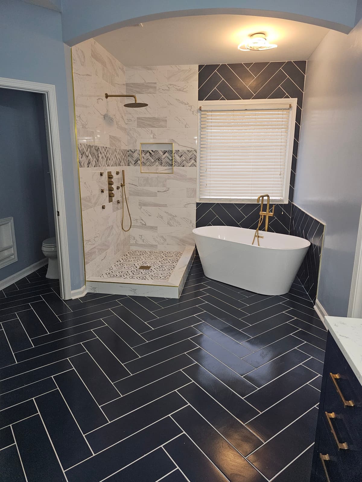 Bathroom with black herringbone tile floor and freestanding tub