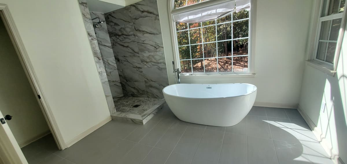 Marble tile walk-in shower beside a freestanding tub
