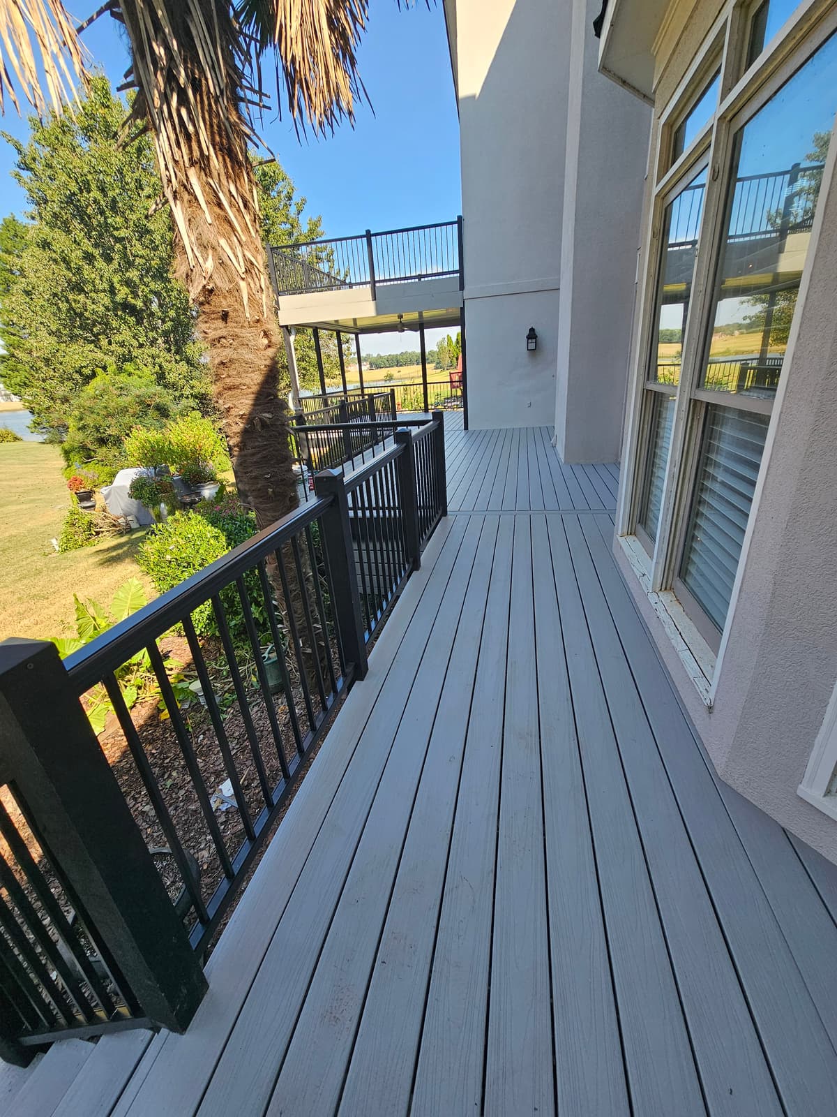Gray composite deck with black aluminum railing overlooking a lake